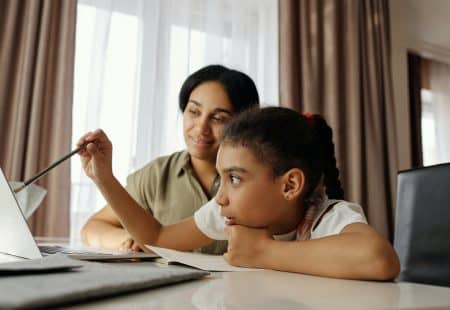 Single mother helping her child at computer with distance learning